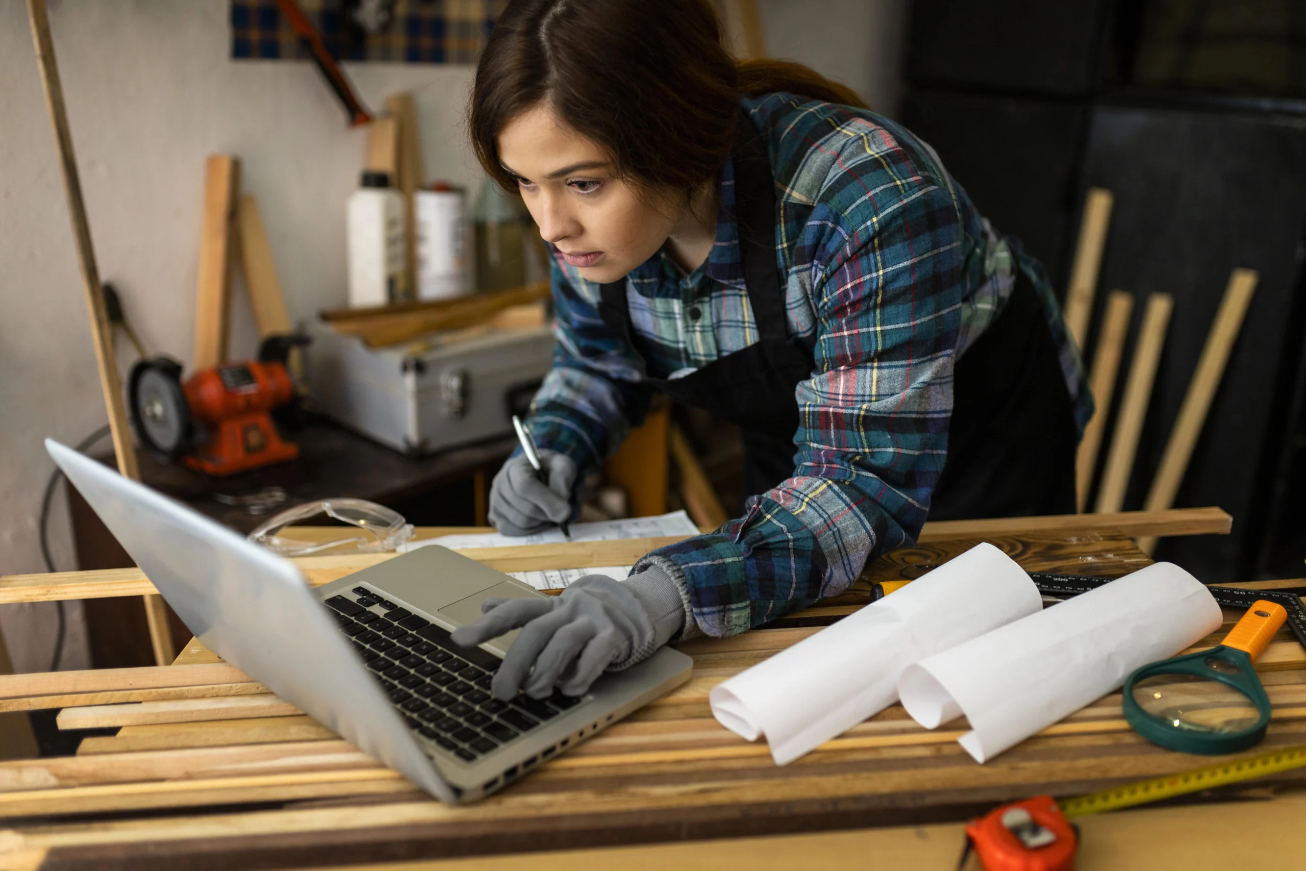 Femme charpentière concentrée travaillant sur un ordinateur pour créer un devis professionnel.